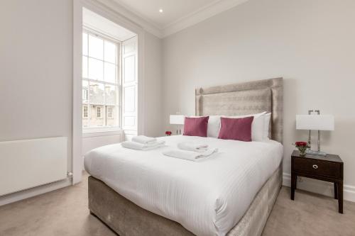 1 dormitorio blanco con 1 cama blanca grande con almohadas rosas en Destiny Scotland - Chisholm Hunter Suites en Edimburgo