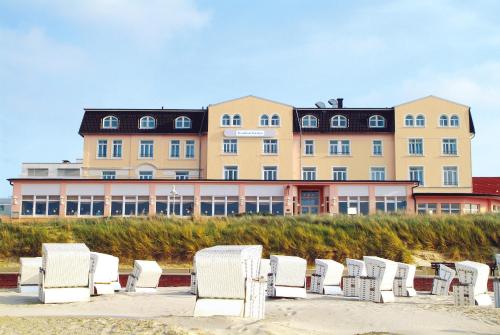 a large building with white chairs on the beach at Strandhotel Gerken in Wangerooge