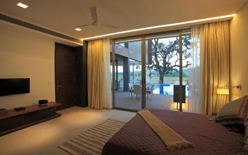 a bedroom with a bed and a tv and a sliding glass door at Luxury Goa Villa in Candolim