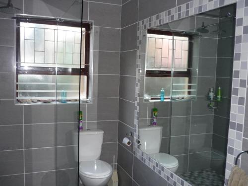 a bathroom with a toilet and a glass shower at A1 Kynaston Guest House bed and breakfast or self catering in Jeffreys Bay