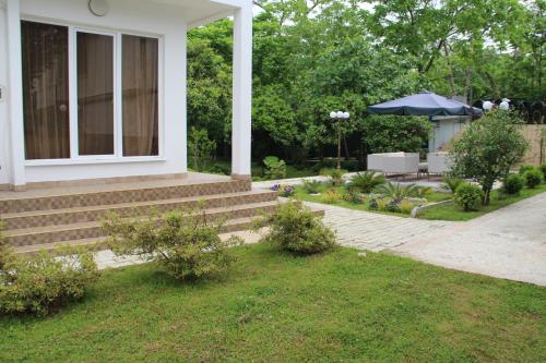 a house with stairs and an umbrella in a yard at Guest House Giorgi in Makhinjauri