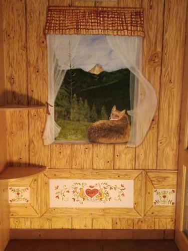 a cat sitting in the window of a house at Hotel Ca' del Bosco in Selva di Cadore