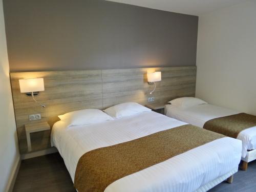 two beds in a hotel room with two lamps at Jura Hotel Restaurant Le Panoramic in Saint-Claude