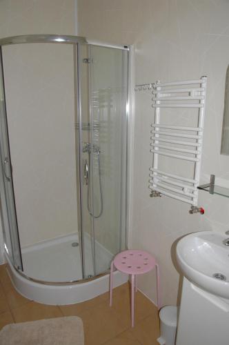 a bathroom with a shower with a pink stool in it at GolfSPA Golfowa Wioska in Szczytna