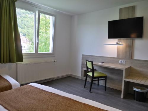 a hotel room with a desk with a chair and a television at Jura Hotel Restaurant Le Panoramic in Saint-Claude