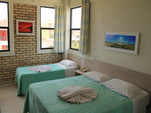 a room with two beds and two windows at Silvestre Praia Hotel in Imbituba