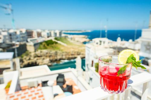 a drink on a ledge with a view of a city at Trame - La Naca sul Porto in Polignano a Mare