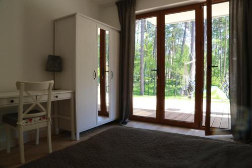 ステグナにあるApartament Mezuvio Baltic Parkのベッドルーム(デスク付)、ガラスのスライドドアが備わります。