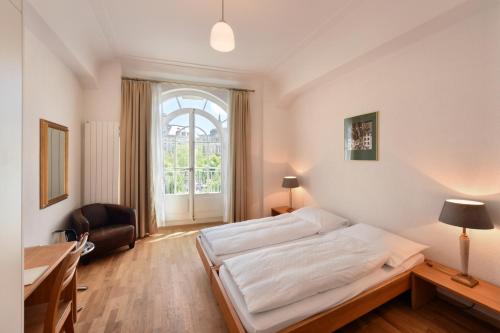 Schlafzimmer mit einem Bett, einem Schreibtisch und einem Fenster in der Unterkunft Hotel National Bern in Bern