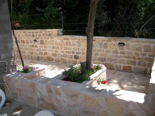 a stone retaining wall with a tree and flowers at Reževići Apartments in Petrovac na Moru