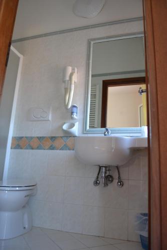 a bathroom with a sink and a mirror and a toilet at Hotel Apis in Rimini