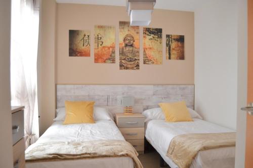 two beds in a room with paintings on the wall at Edimar 9 - Fincas Arena in Benidorm