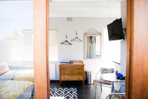 Cobie Apartment في ستيلينبوش: غرفة نوم بسرير وطاولة وتلفزيون