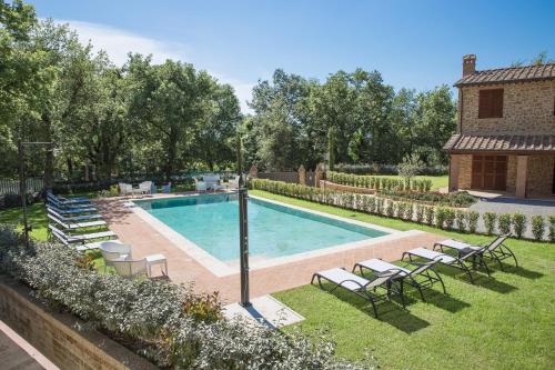 a swimming pool in a yard with chairs and a house at Borgo Poggiardelli in Montepulciano