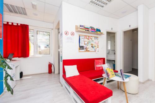 a living room with a red couch and a table at Hostel Petra Marina in Dubrovnik