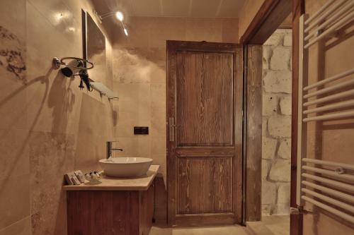 a bathroom with a sink and a wooden door at Guzide Cave Hotel in Göreme