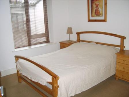 キンセールにあるLuxury Town Centre Apartmentのベッドルーム1室(木製ベッド1台、窓付)