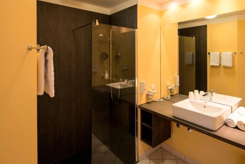 a bathroom with a sink and a shower at Thermalis - Das Boardinghouse im Kurpark Bad Hersfeld in Bad Hersfeld