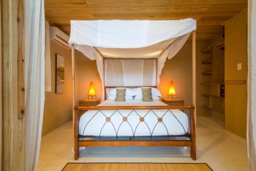a bedroom with a canopy bed with two lamps at Castara Retreats in Castara
