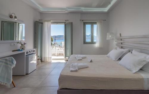 a white bedroom with a large bed and a balcony at Olea Bay Hotel in Adamas