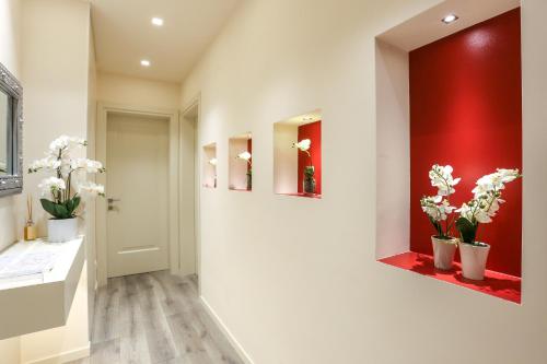 un couloir avec des fleurs blanches sur un mur rouge dans l'établissement Rialto Suite 1602, à Venise