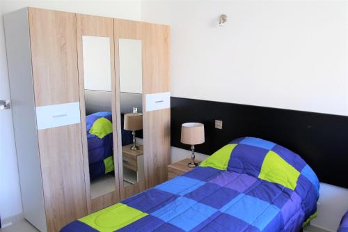Un dormitorio con una cama azul y amarilla y espejos en Chimes - Gozo Bellevue Homes en Victoria