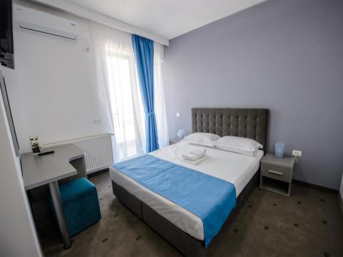 a bedroom with a bed and a desk and window at Vila La Mer Mamaia Nord in Mamaia Nord