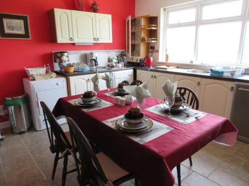 cocina con mesa y mantel rojo en Leam Cottage, en Belmullet
