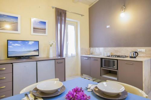 a kitchen with a table and a tv on a counter at Iolanda Apartment 30m from Seaside in Alghero