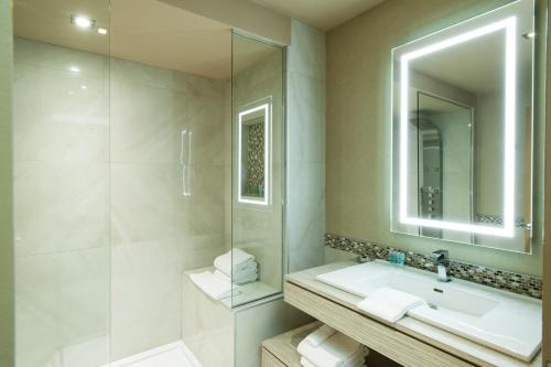 a white bathroom with a sink and a mirror at Le Chabrol Hotel & Suites in Montreal