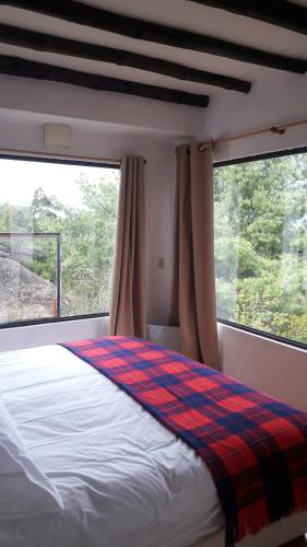 a bedroom with a bed and two large windows at Farallones de Sutatausa El Rincón in Sutatausa