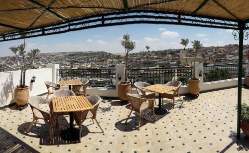 a patio with tables and chairs on a roof at Riad Batchisarai in Fès