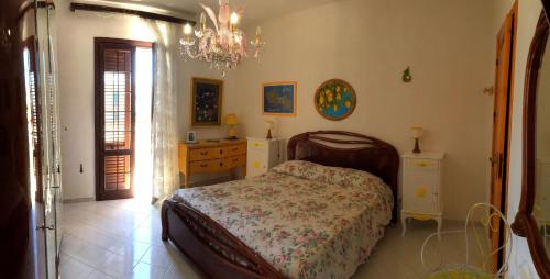 una camera con letto, cassettiera e lampadario a braccio di Guest House Al Giardino dei Limoni a Favignana