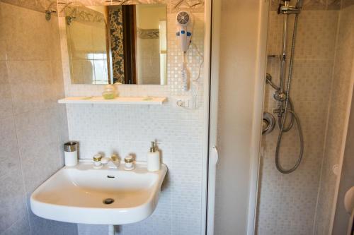biała łazienka z umywalką i prysznicem w obiekcie La Quiete w mieście Anagni