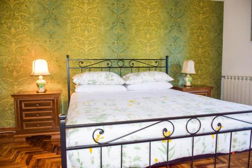 a bedroom with a bed with green wallpaper and two lamps at La Quiete in Anagni