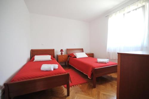 a bedroom with two beds with red sheets and a window at Villa Luna with Seaview in Petrcane