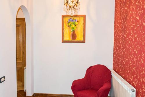 a red chair in a hallway with a picture on the wall at La Quiete in Anagni