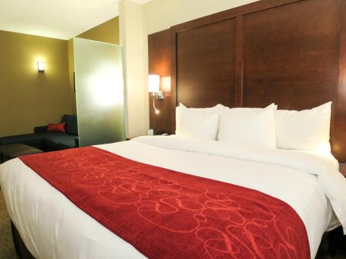 a hotel room with a large bed with a red blanket at Comfort Suites Regina in Regina