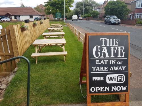 una fila de mesas de picnic a un lado de la carretera en Sutherlands Hotel, en Gateshead