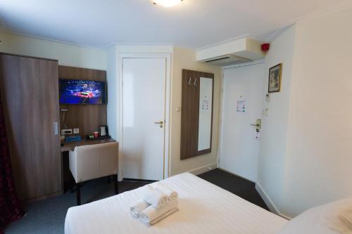 a room with a bed and a desk and a television at Hotel Park Plantage in Amsterdam