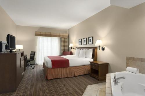a hotel room with a bed and a bath tub at Country Inn & Suites by Radisson, Cedar Rapids Airport, IA in Cedar Rapids