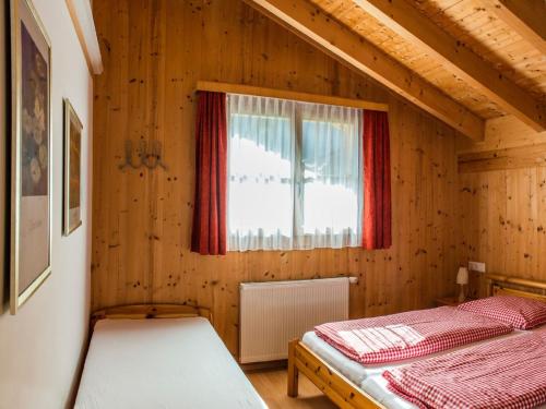 2 Betten in einem Holzzimmer mit Fenster in der Unterkunft Ferienhaus Valleu in Bartholomäberg