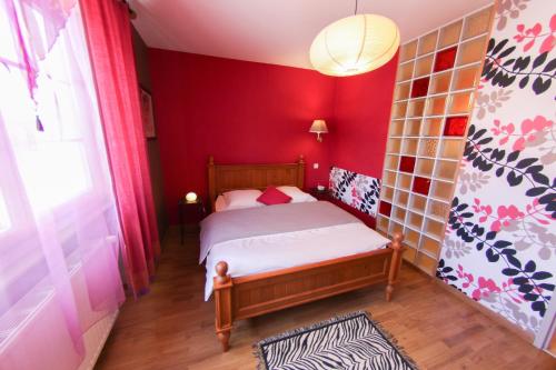 a small bedroom with a bed with red walls at Domaine du Port Sainte Marie in Maizières-lès-Vic