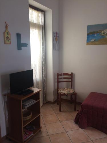 ein Wohnzimmer mit einem TV und einem Stuhl in der Unterkunft Bixio Apartments in San Vito lo Capo
