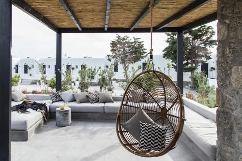 a rattan swing hanging from a patio with a couch at My Mykonos Hotel in Mýkonos City