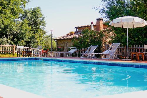 a swimming pool with two chairs and an umbrella at Casale Vigna Carbona in Gavorrano