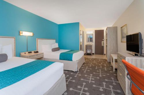 ein Hotelzimmer mit zwei Betten und einem Flachbildfernseher in der Unterkunft Howard Johnson by Wyndham Mystic in Mystic