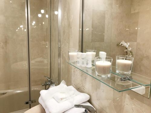 a bathroom with a glass shelf with candles and a shower at Vivaldi Boutique Suites Jardines del Mar in Marbella
