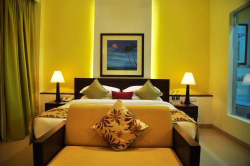 a bedroom with a bed with a couch and two lamps at Kyriad Prestige Calangute Goa by OTHPL in Calangute