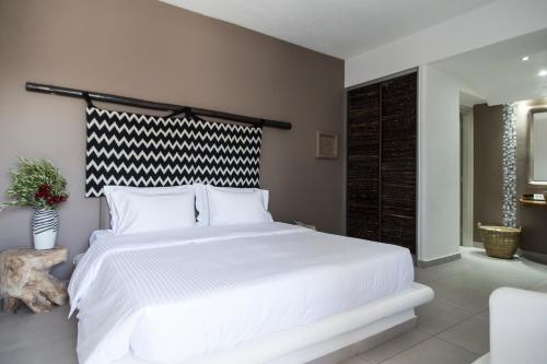 a bedroom with a large bed with white sheets at My Mykonos Hotel in Mýkonos City